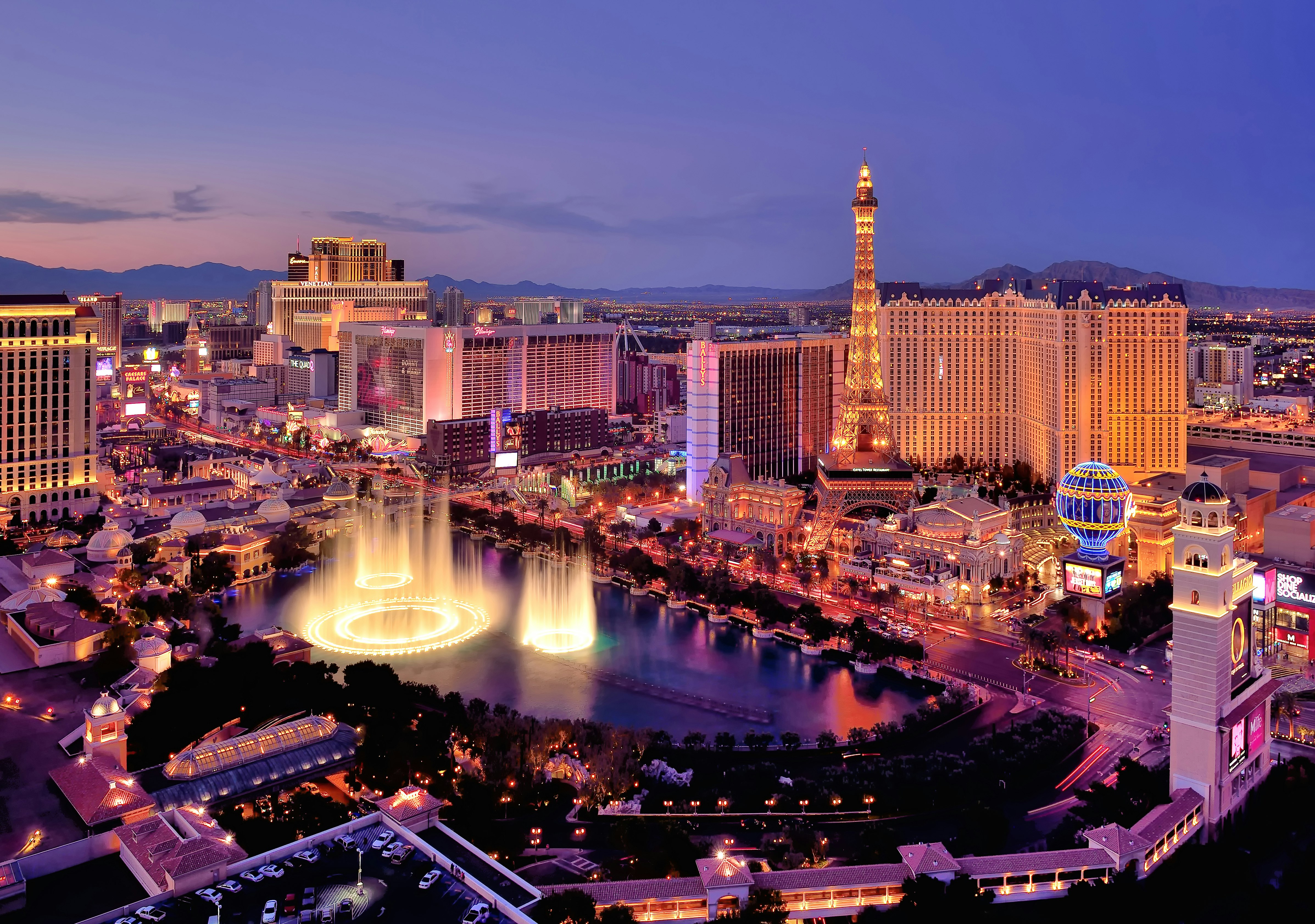 The Las Vegas strip with the fountains of the Bellagio leaping into the air photographed at dusk. 